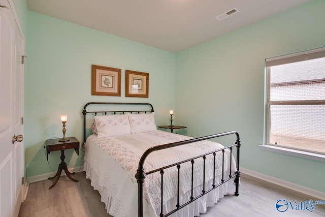 bedroom featuring visible vents, baseboards, and wood finished floors