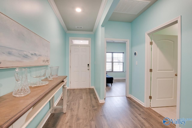 entryway with crown molding, wood finished floors, visible vents, and baseboards