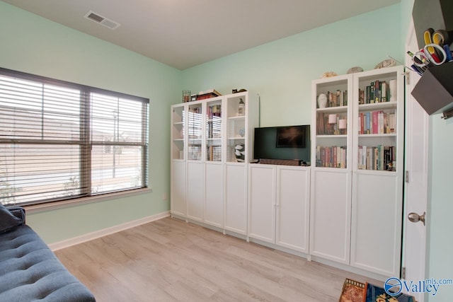 living room with light wood finished floors, visible vents, and baseboards