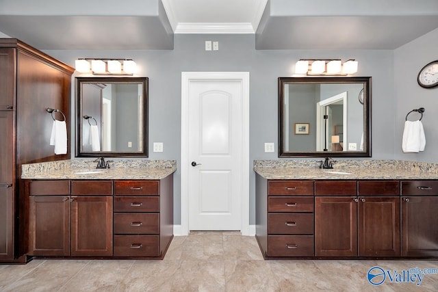 full bathroom with ornamental molding, two vanities, a sink, and baseboards