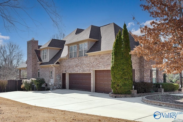 view of front of home with roof with shingles, driveway, a chimney, and brick siding