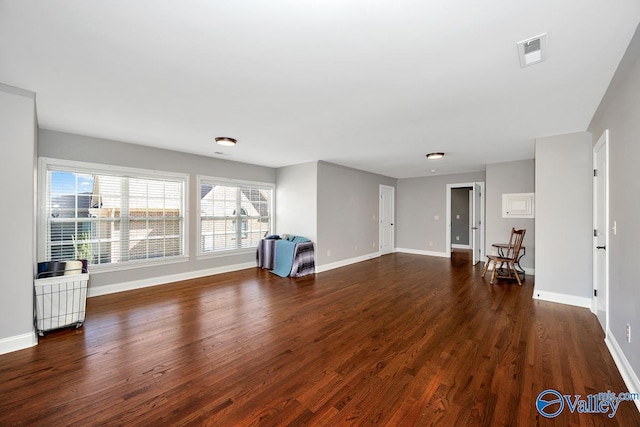 unfurnished living room with baseboards, visible vents, and wood finished floors