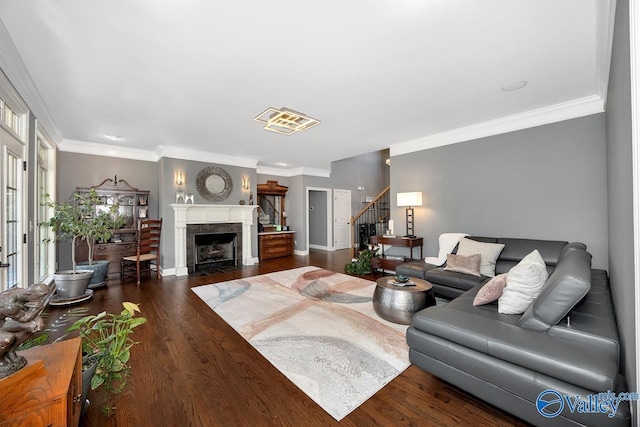 living room featuring stairway, dark wood finished floors, a tile fireplace, and crown molding