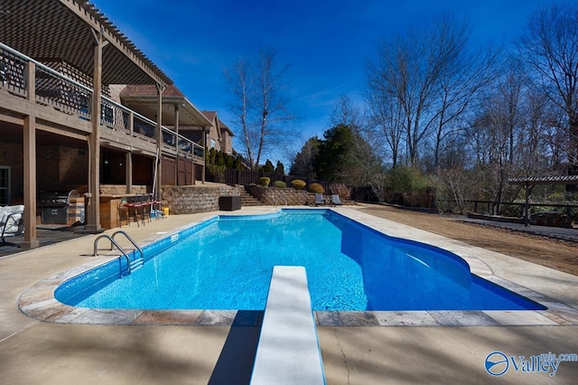 pool featuring an outdoor kitchen, a patio, outdoor dry bar, a diving board, and a pergola