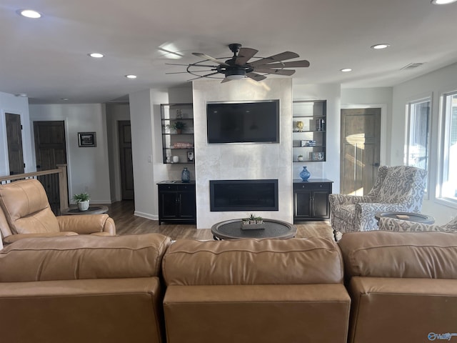 living room with hardwood / wood-style flooring, ceiling fan, and a fireplace