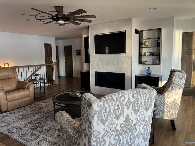 living room featuring dark hardwood / wood-style flooring, a tiled fireplace, and ceiling fan