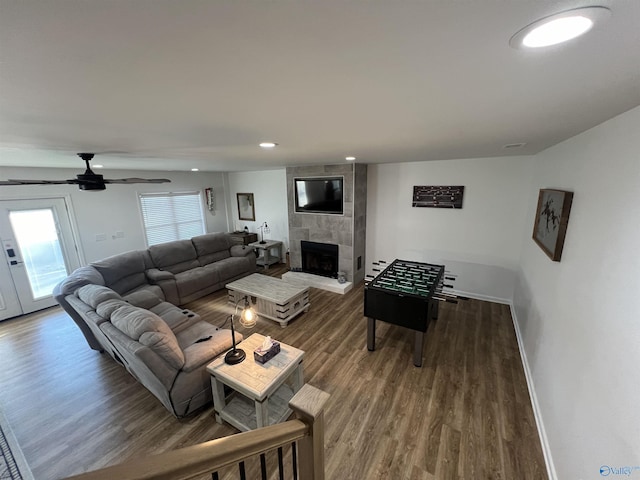 living room featuring ceiling fan, dark wood-type flooring, and a fireplace