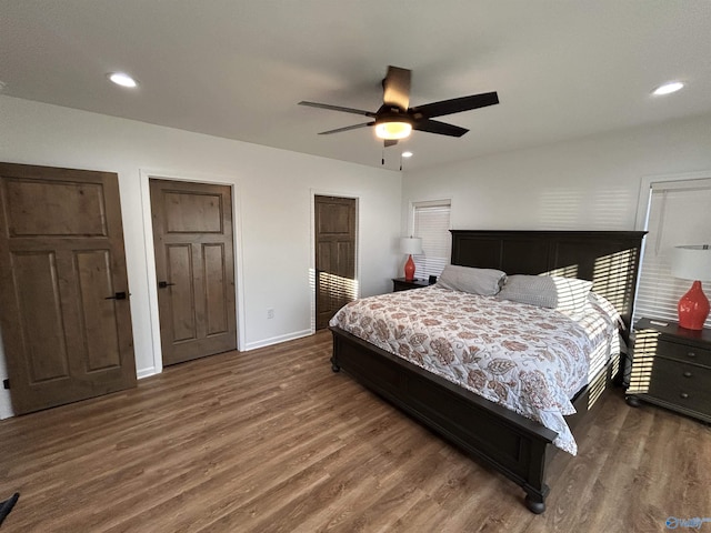 bedroom featuring two closets, dark wood-type flooring, and ceiling fan