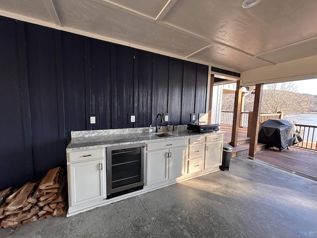 kitchen with white cabinetry, sink, light stone countertops, and beverage cooler