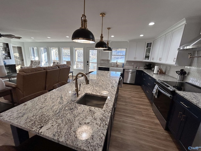 kitchen featuring sink, hanging light fixtures, appliances with stainless steel finishes, an island with sink, and white cabinets