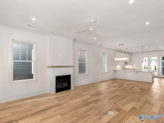 unfurnished living room with crown molding, sink, ceiling fan, and light hardwood / wood-style flooring