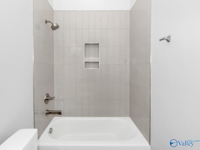 bathroom with toilet and tiled shower / bath combo