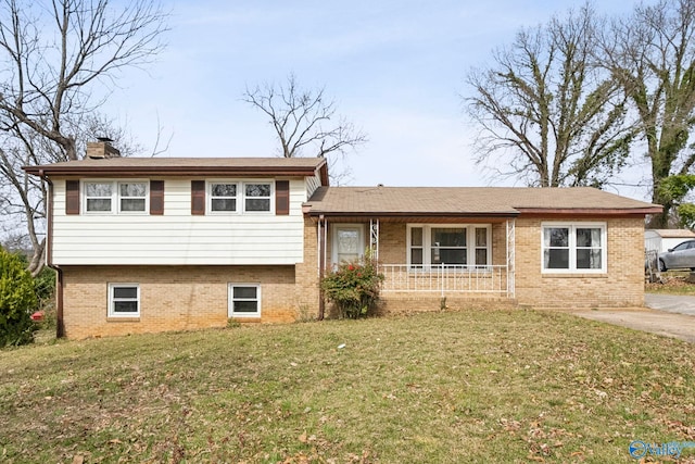 tri-level home with a front lawn, brick siding, a porch, and a chimney