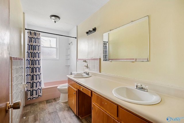 full bathroom with wood finished floors, double vanity, a sink, shower / bath combination with curtain, and toilet