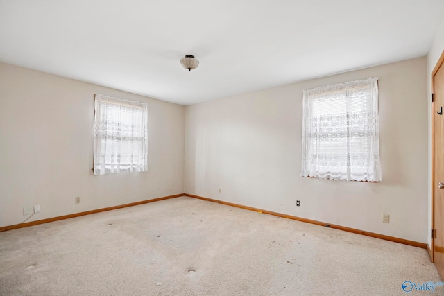 carpeted empty room featuring a healthy amount of sunlight and baseboards