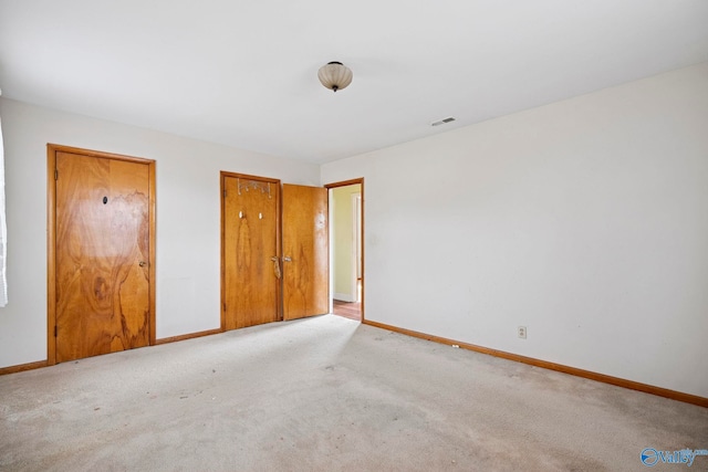 unfurnished bedroom with carpet flooring, baseboards, and visible vents