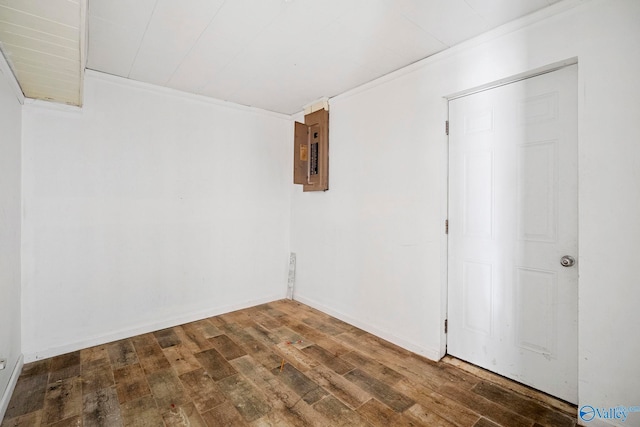 empty room with electric panel, baseboards, and hardwood / wood-style floors