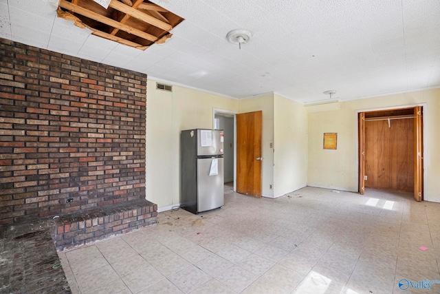 interior space with visible vents, brick wall, and baseboards