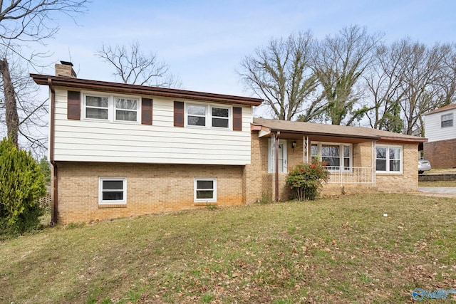 split level home featuring a front lawn, brick siding, and a chimney