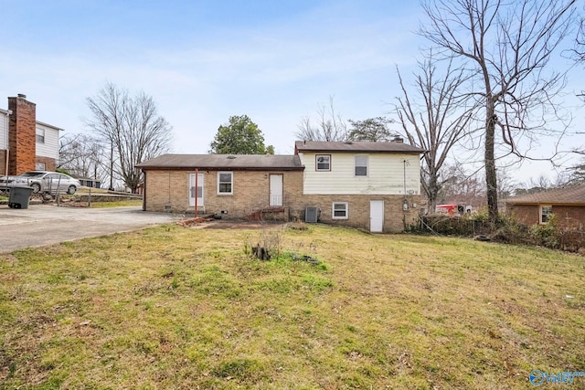 tri-level home with brick siding, central air condition unit, driveway, and a front yard