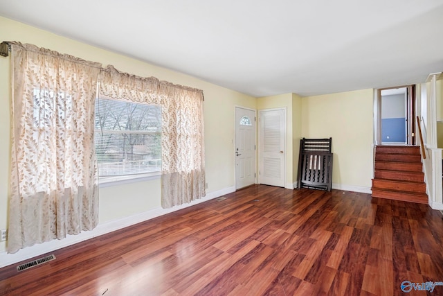 unfurnished room with stairway, wood finished floors, visible vents, and baseboards