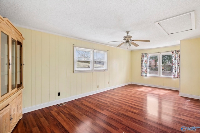 spare room with visible vents, baseboards, attic access, wood finished floors, and a textured ceiling