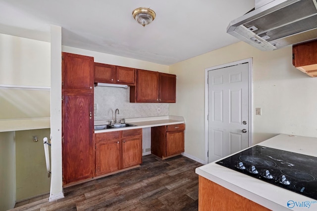 kitchen with dark wood-style floors, a sink, light countertops, black electric stovetop, and tasteful backsplash