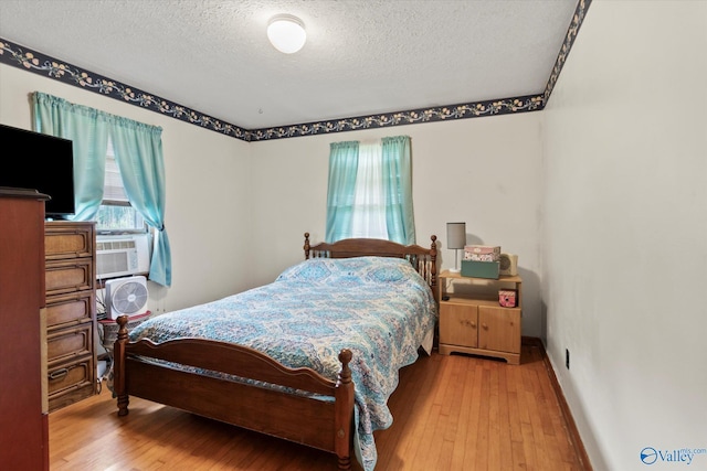 26740 Nick Davis Rd, Athens, AL 35613 - bedroom with cooling unit, a textured ceiling, hardwood / wood-style flooring, and baseboards