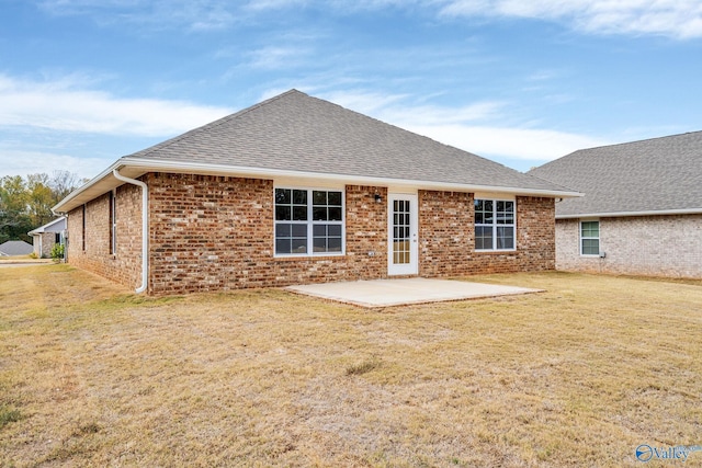 back of property featuring a yard, brick siding, a patio, and roof with shingles