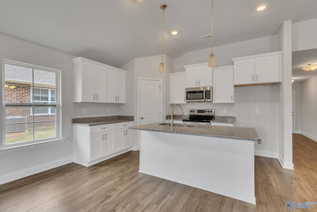 kitchen featuring stainless steel appliances, a sink, white cabinetry, hanging light fixtures, and an island with sink