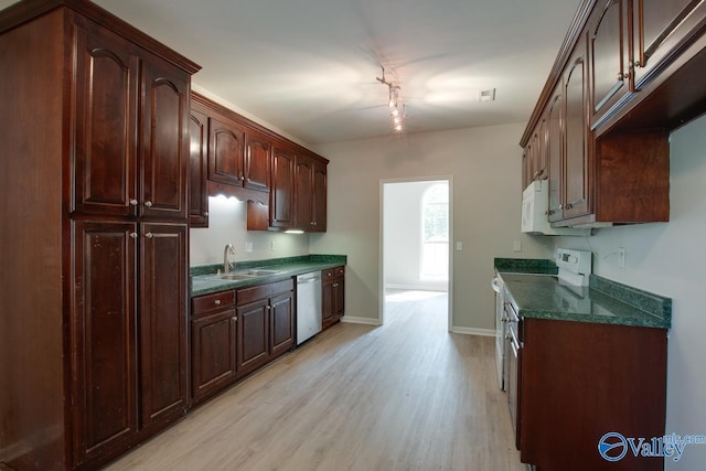 kitchen with a sink, white appliances, light wood-style flooring, baseboards, and dark brown cabinets