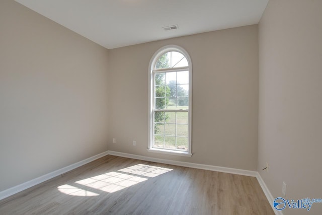 unfurnished room with visible vents, wood finished floors, and baseboards