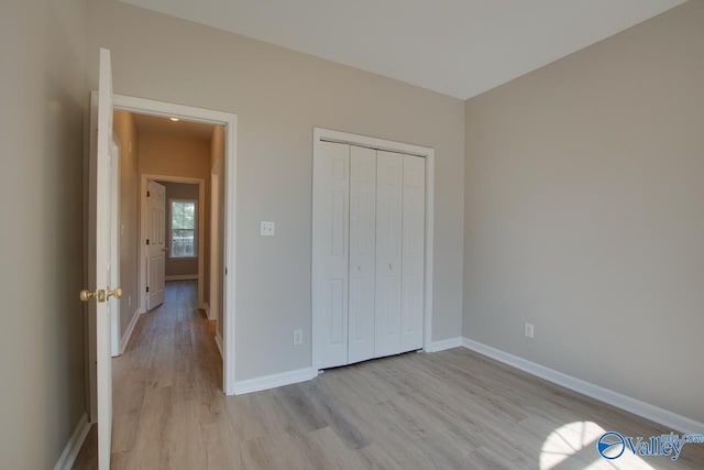 unfurnished bedroom with a closet, baseboards, and light wood-style floors
