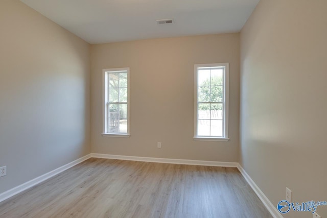 spare room with a healthy amount of sunlight, visible vents, and light wood-type flooring