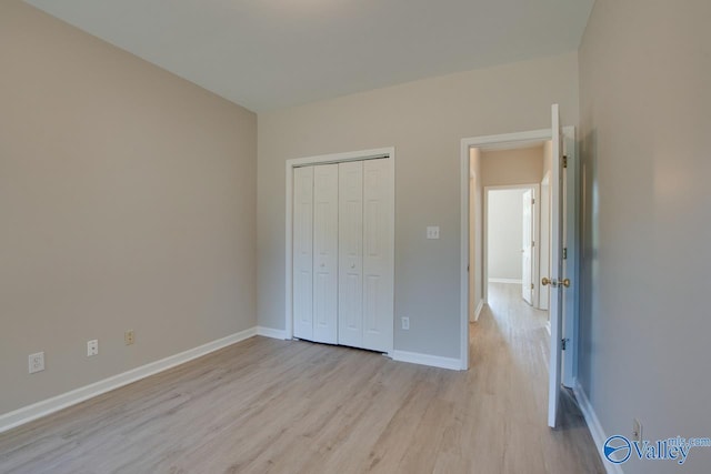 unfurnished bedroom with light wood-style floors, a closet, and baseboards
