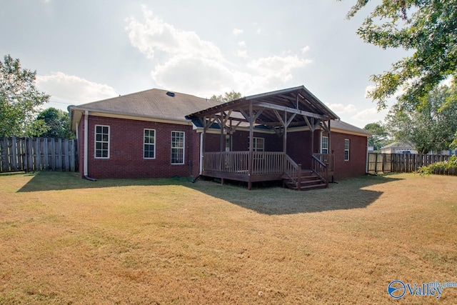 back of house featuring a lawn, brick siding, a wooden deck, and a fenced backyard