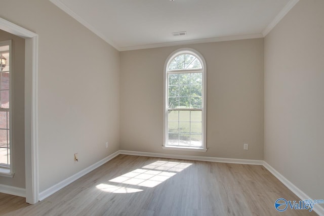 spare room with wood finished floors, crown molding, and baseboards