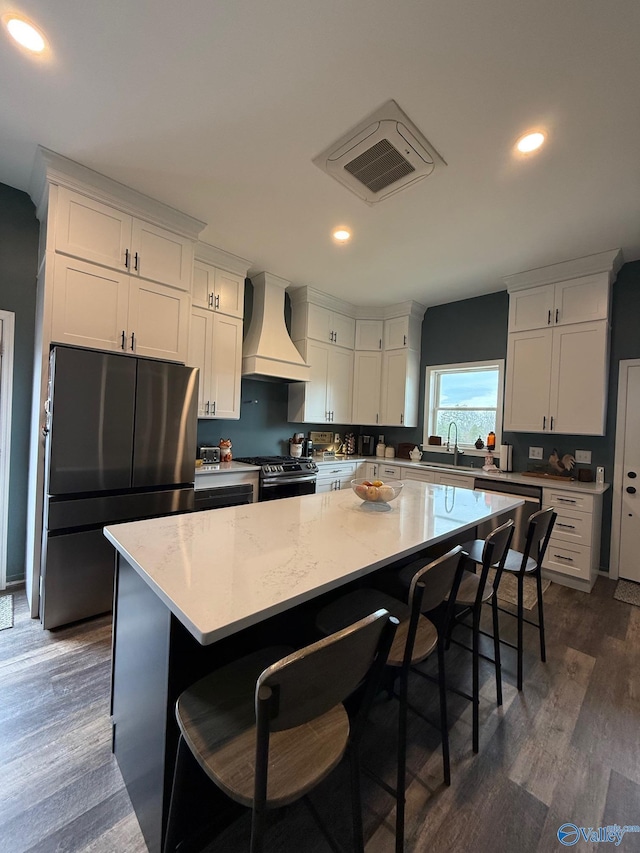 kitchen featuring premium range hood, appliances with stainless steel finishes, a center island, and white cabinets