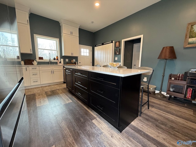 kitchen featuring a barn door, a center island, a breakfast bar area, and white cabinets