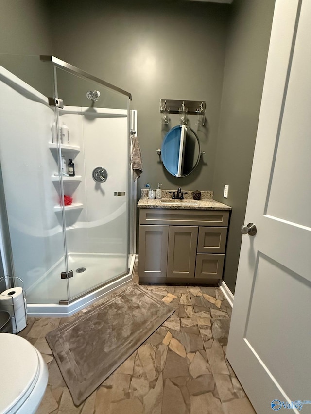 bathroom featuring a shower with door, vanity, and toilet