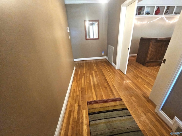 corridor with visible vents, baseboards, and wood finished floors