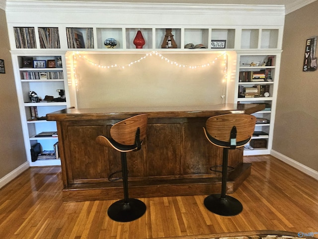 bar with ornamental molding, baseboards, and wood finished floors