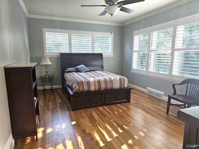 bedroom with visible vents, wood finished floors, baseboards, and ornamental molding