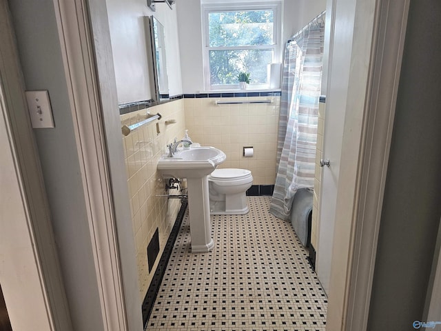 bathroom with wainscoting, curtained shower, toilet, and tile walls