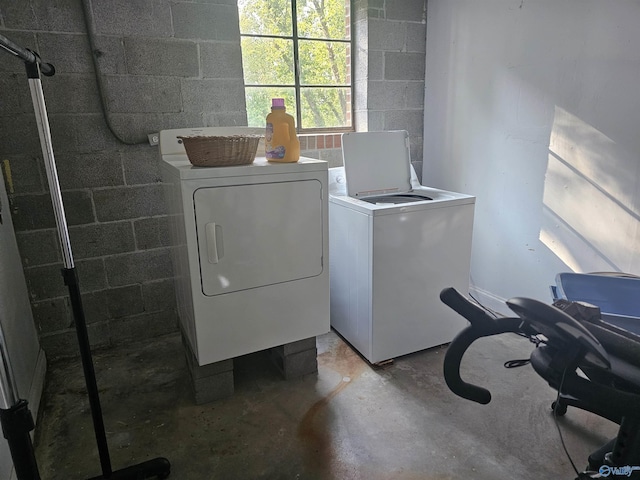 laundry room featuring laundry area, concrete block wall, and separate washer and dryer