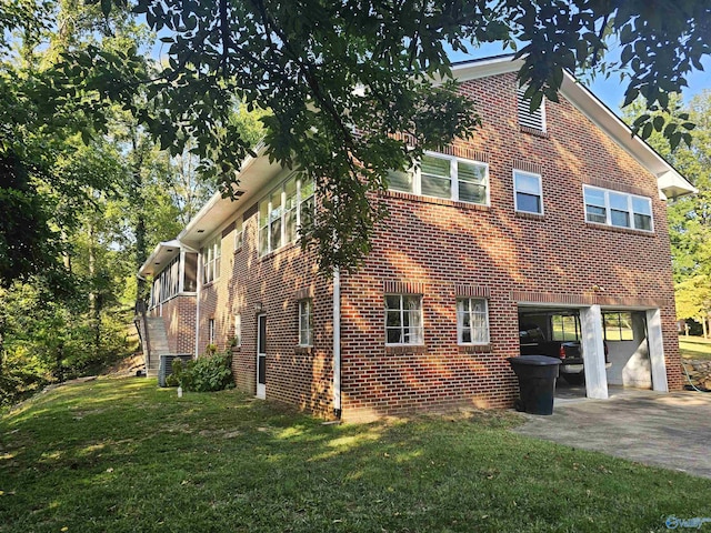 view of side of property with an attached garage, a yard, brick siding, and driveway