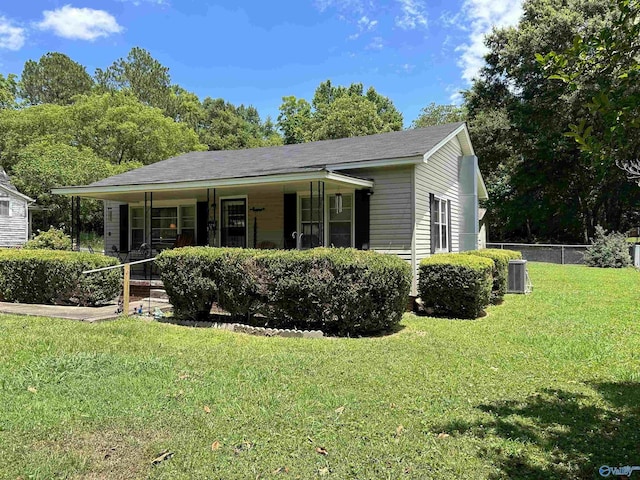 view of front of home with central air condition unit, a porch, fence, and a front lawn