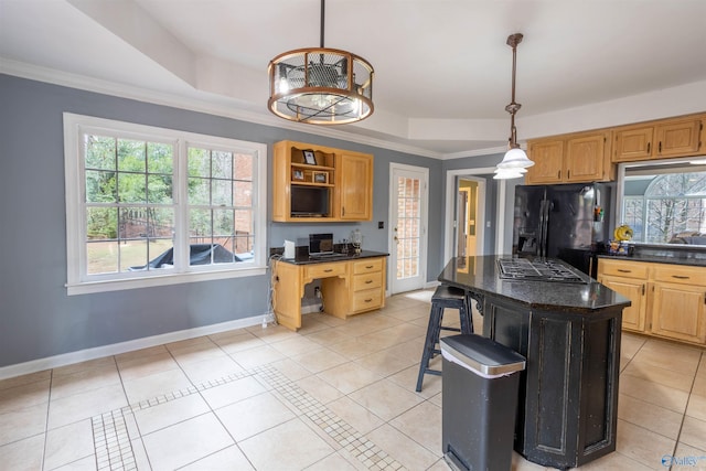 kitchen with a center island, a tray ceiling, black refrigerator with ice dispenser, and hanging light fixtures