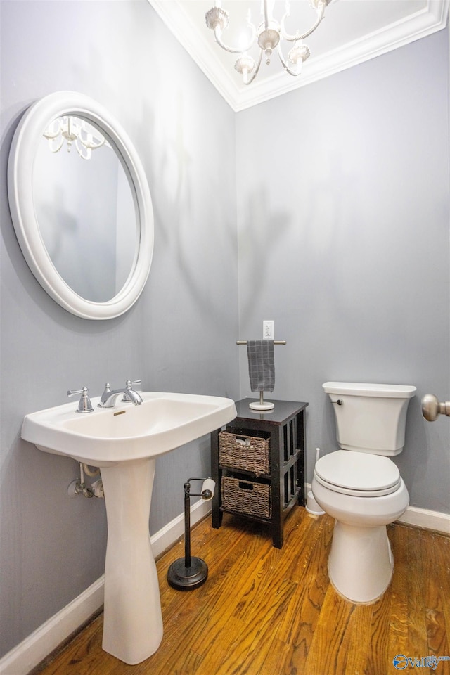 bathroom with ornamental molding, sink, a notable chandelier, hardwood / wood-style floors, and toilet