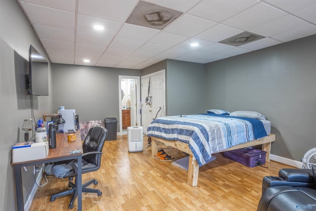 bedroom with a paneled ceiling and light hardwood / wood-style floors